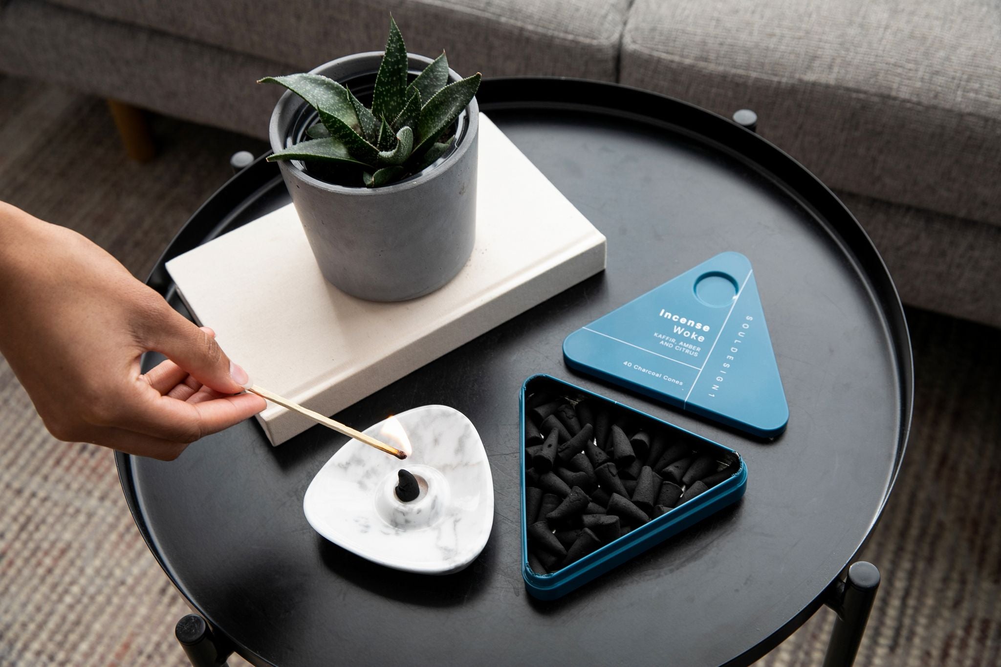 Lighting charcoal incense cones in white marble burner.
